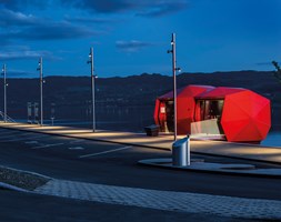 Badet i lys! Genskinnet fra de blanke, Ferrari-røde facadeplader skaber et spændende udtryk i nattemørket langs Mjøsa.                              Foto: Tomasz Majewski